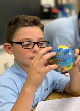 Guardian Angels Regional School student using a mini globe as a classroom resource