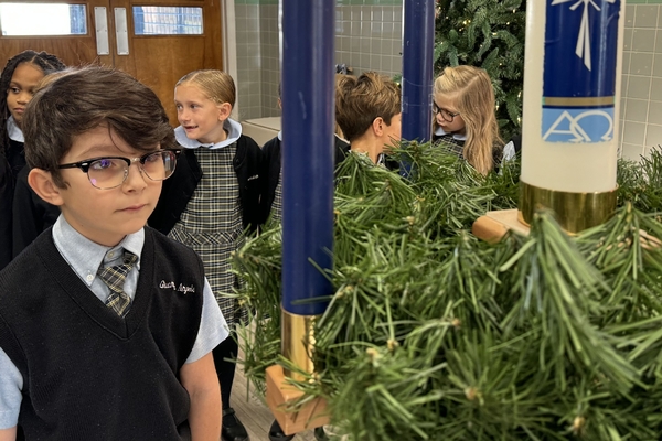 Guardian Angels Regional School student looking at one of the purple candles in our Advent wreath